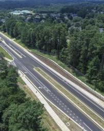 两车道高速公路的鸟瞰图，两边都是绿树